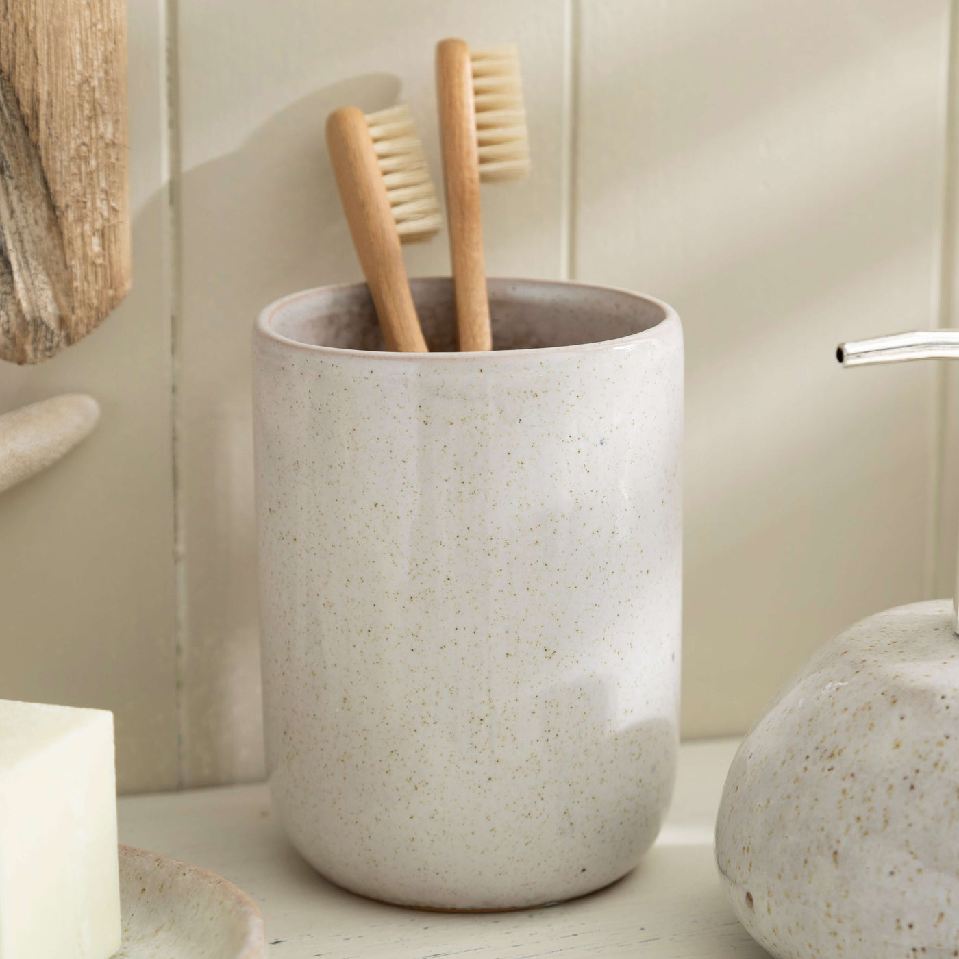 Stone effect ceramic toothbrush holder with bamboo brushes in modern bathroom setting.