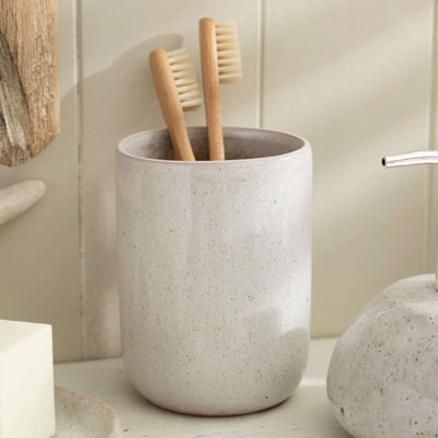 Stone effect ceramic toothbrush holder with bamboo brushes in modern bathroom setting.