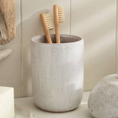 Stone effect ceramic toothbrush holder with wooden toothbrushes, adding natural elegance to bathroom decor.