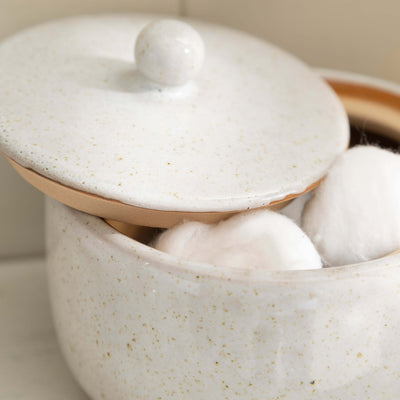 Stone effect ceramic lidded jar with cotton balls, part of a stylish bathroom accessory set for natural elegance.