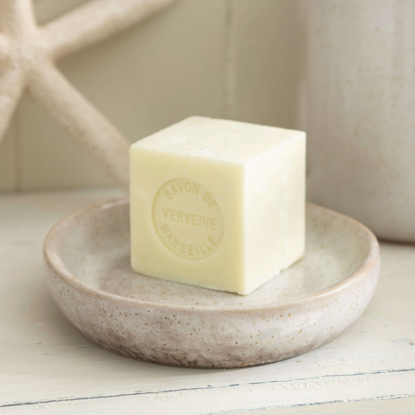 Stone effect ceramic soap dish with a cube of green soap, adding natural elegance to bathroom decor.