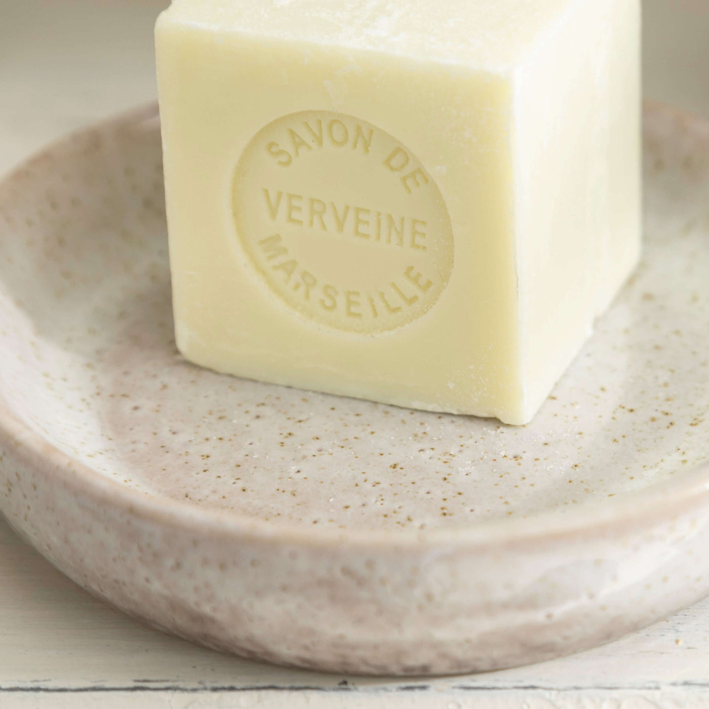 Stone effect ceramic soap dish with a bar of verbena Marseille soap placed on top, showcasing natural elegance and texture.